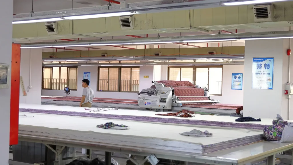 Automated clothing factory production line features computer-controlled cutting machines to achieve faster production lead times for OEM apparel.