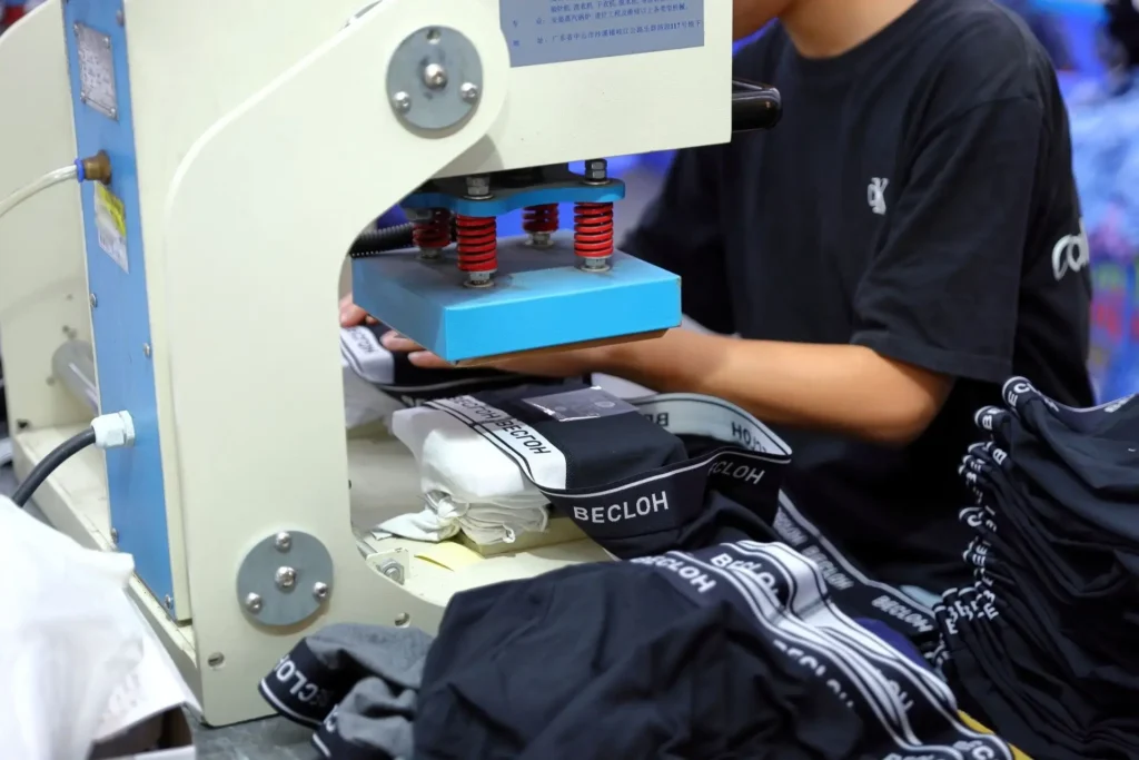 Skilled artisan executing detailed custom heat transfer on private label men's underwear during a low MOQ production run.